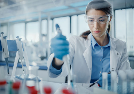 Photo of a lab tech injecting red liquid into test tubes