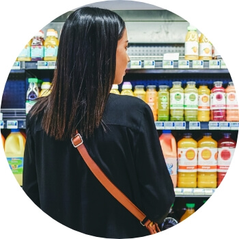 Photo of a brunette woman shopping in a juice aisle at a grocery store