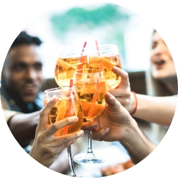 Photo of people clinking four glasses with alcoholic beverages and red straws in them