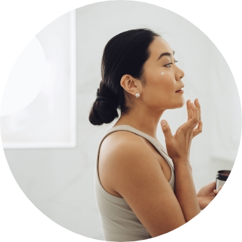 Photo of a woman with black hair applying face lotion