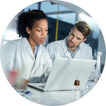 Photo of two lab techs looking at a laptop screen